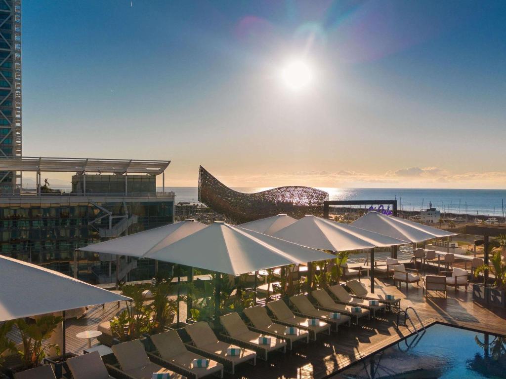a resort with a pool and tables and umbrellas at Sofitel Barcelona Skipper in Barcelona