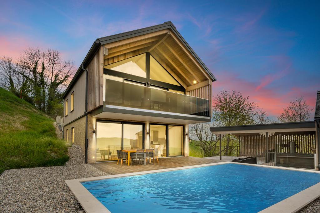 a house with a swimming pool in front of it at Luxus Chalet Max mit Poolnutzung in Glanz an der Weinstraße