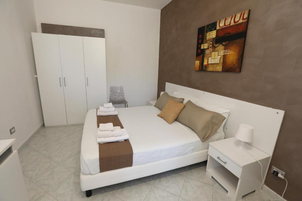 a bedroom with a white bed and a white cabinet at Helios Rooms in Quartu SantʼElena