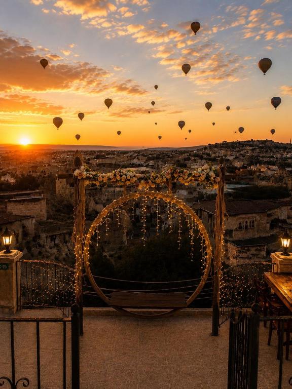 a sunset with hot air balloons flying over a city at Sakli Cave House in Avanos