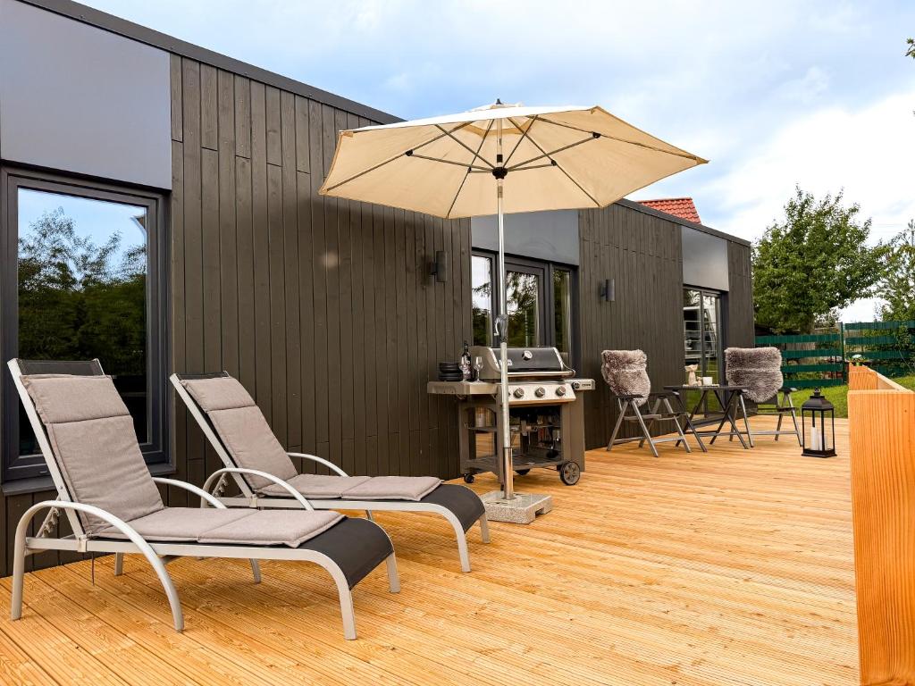 a patio with chairs and an umbrella and a grill at FewoCrew Devils Cabin Premium Tiny House nahe Teufelsmauer in Wienrode