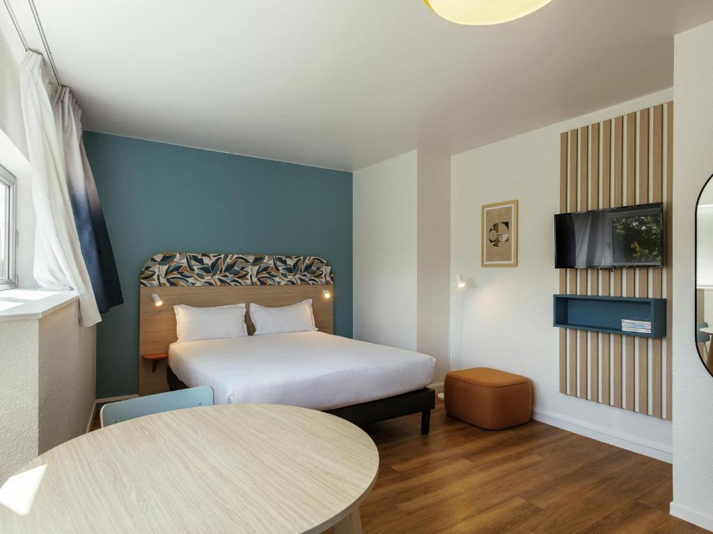 a small room with a bed and a table at Aparthotel Adagio Access Paris La Villette in Paris