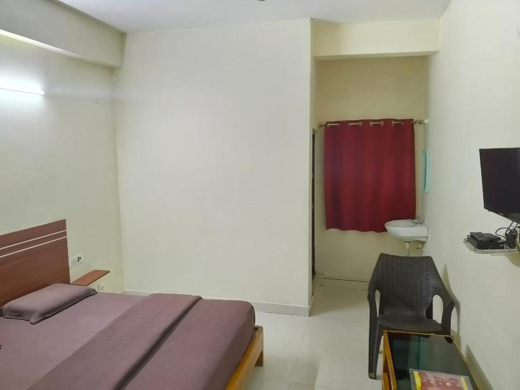 a bedroom with a bed and a chair and a television at mythriinn in Araku