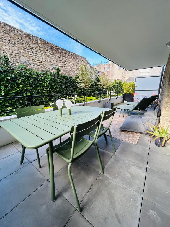 a green table and chairs on a patio at L'Hermine terrasse et parking, 500 plage in Concarneau