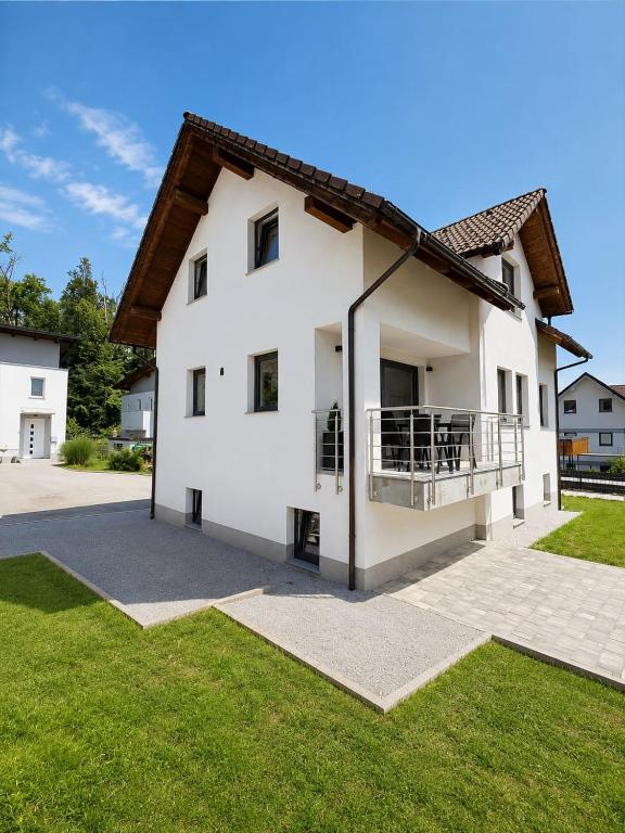a white house with a balcony and grass at The River House in Mavčiče