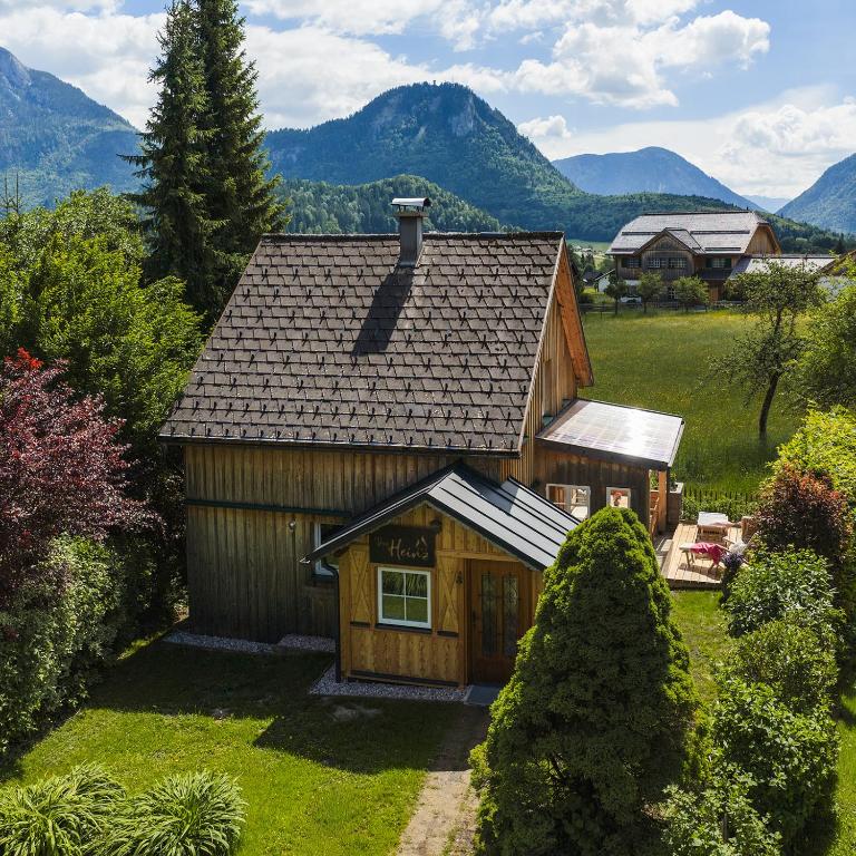 a small wooden house with mountains in the background at Das Heinz Altaussee - Your Austrian Home in Altaussee