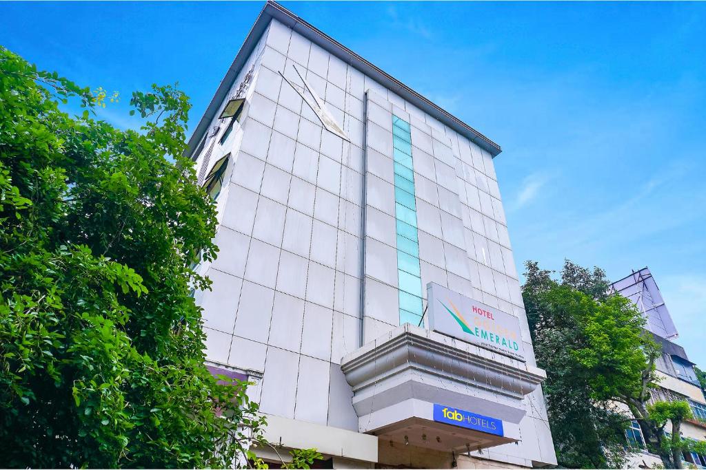 a tall white building with a sign on it at FabHotel Golden Emerald in Pune