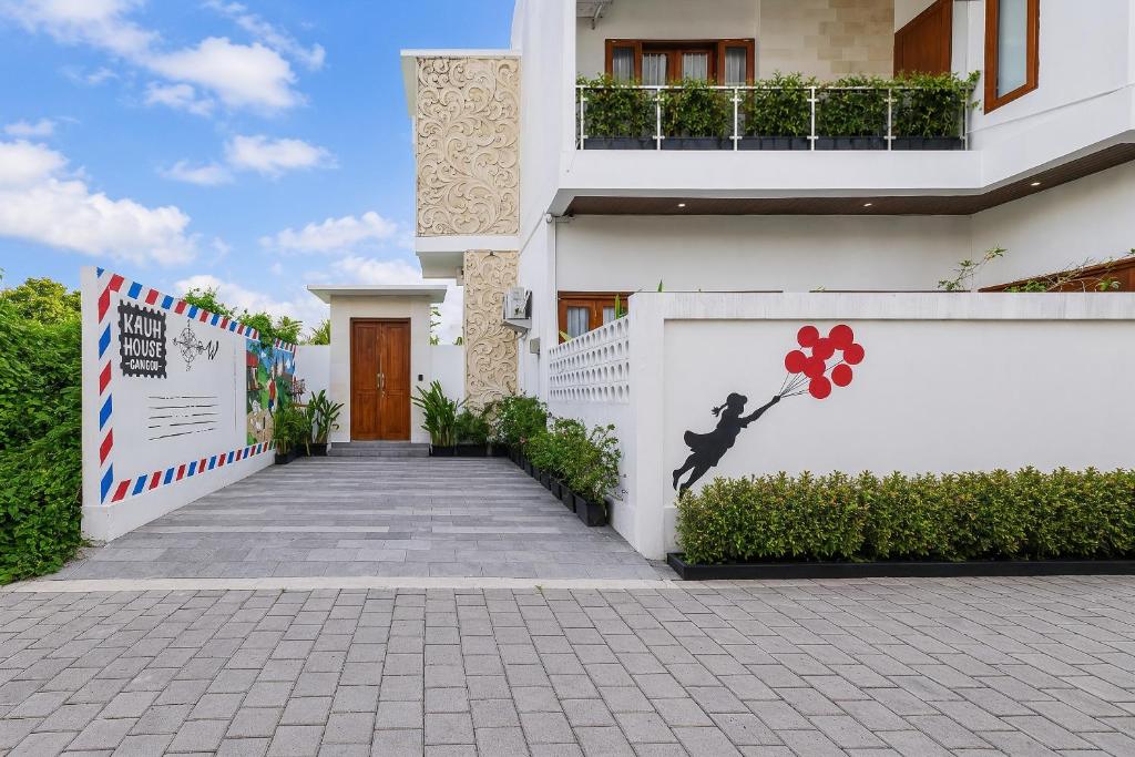 a white building with a wall with a mural of a person dancing at KAUH House Canggu in Tumbak Bayuh