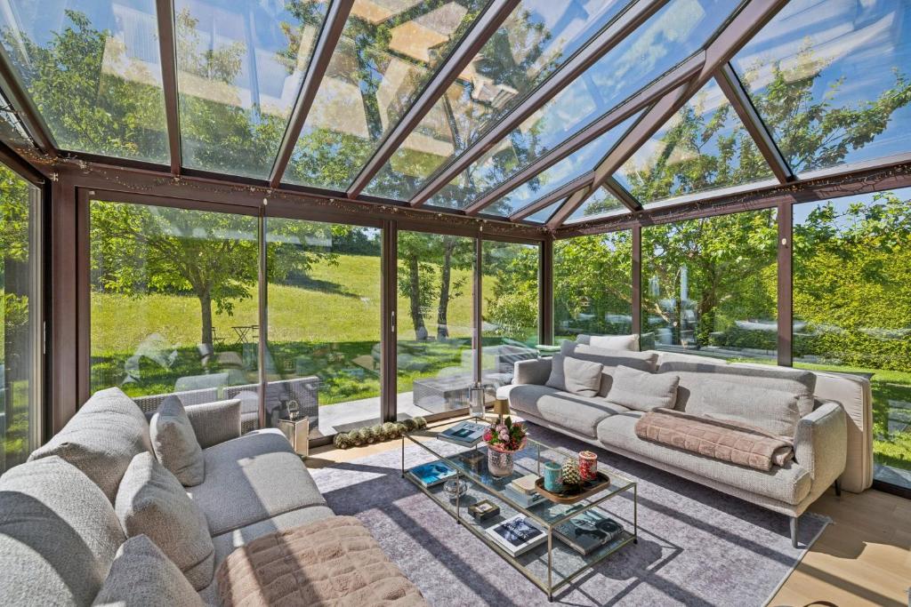 a glass conservatory with couches and a table at Chalet Niva by Mrs Miggins in Lens