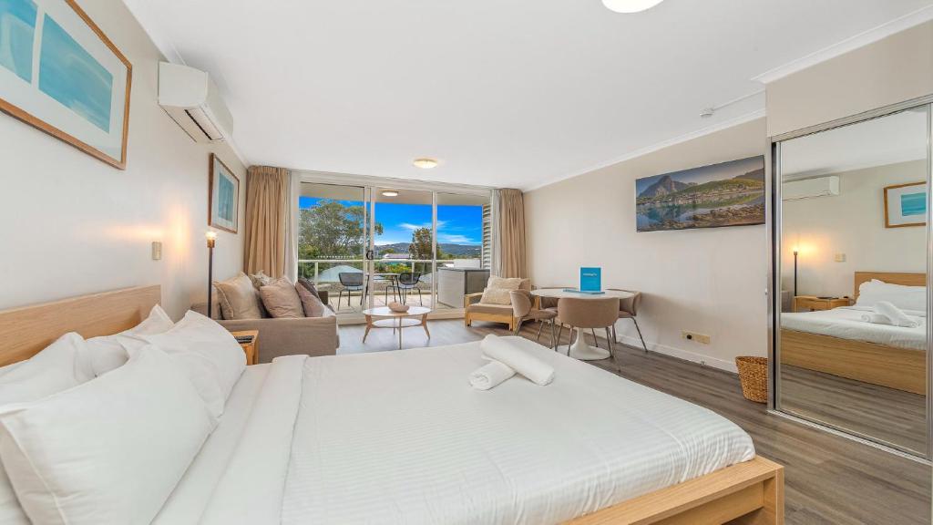 a bedroom with a bed and a living room at Studio Oasis - Ettalong Beach Resort in Ettalong Beach