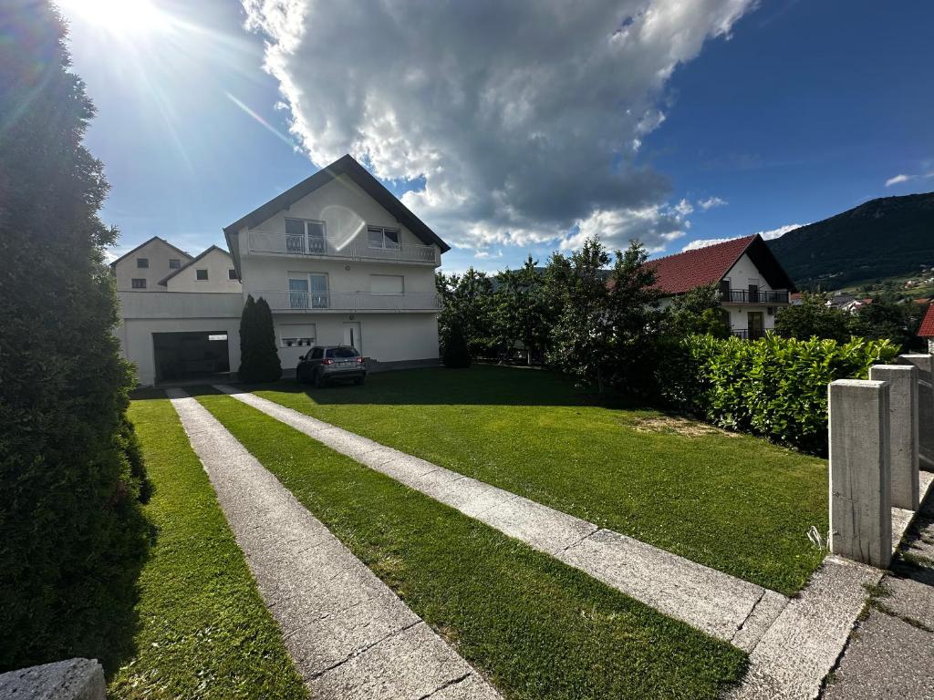 a house with a grassy yard with a driveway at Apartmani Ivana in Prozor