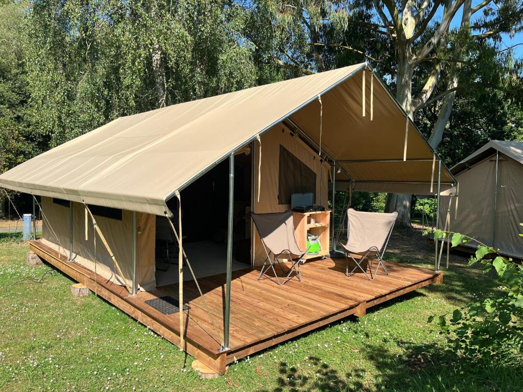 a canvas tent with two chairs and a deck at Camping Onlycamp les etangs in La Richardais