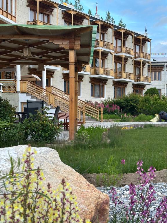 a large building with a wooden pergola in a garden at Raku Guest House - A Peaceful Stay in the Heart of Leh in Leh