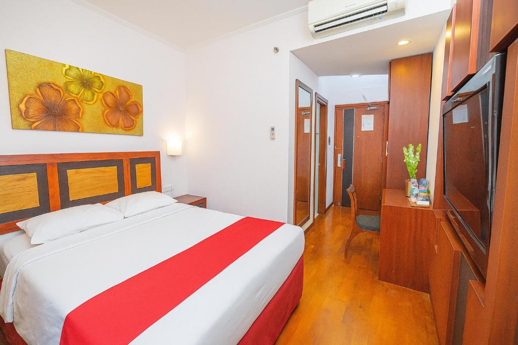 a bedroom with a bed with a red and white blanket at Lampion Hotel Solo in Grogol