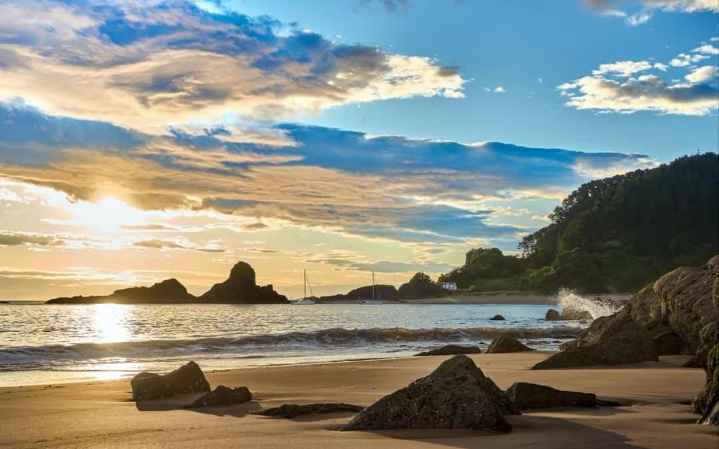 a sunset on a beach with rocks in the sand at Apartamento Delfina in Ondárroa