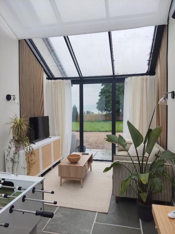 a living room with a large window and a table at Woodville Apartment in Rathmullan