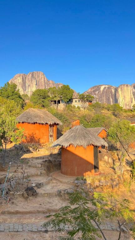 two small houses with thatched roofs in a field at Tsarasoa Lodge in Ambalavao