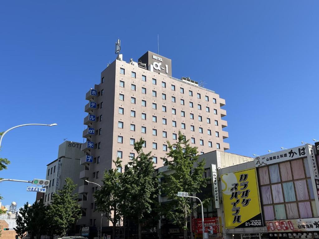 a tall white building with a sign on top of it at Hotel Alpha-One Yonago in Yonago