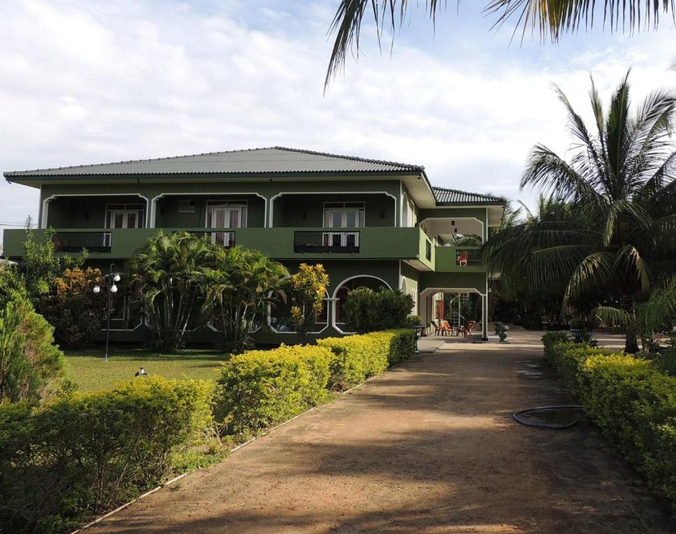 a green house with a palm tree in front of it at Nandawanam Guest House Pasikuda in Kalkudah
