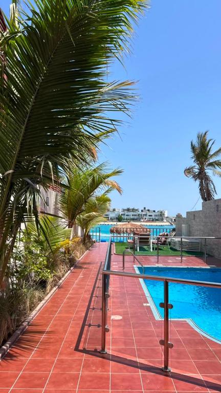 a swimming pool with palm trees next to a resort at فيلا درة العروس 2 in Durat Alarous