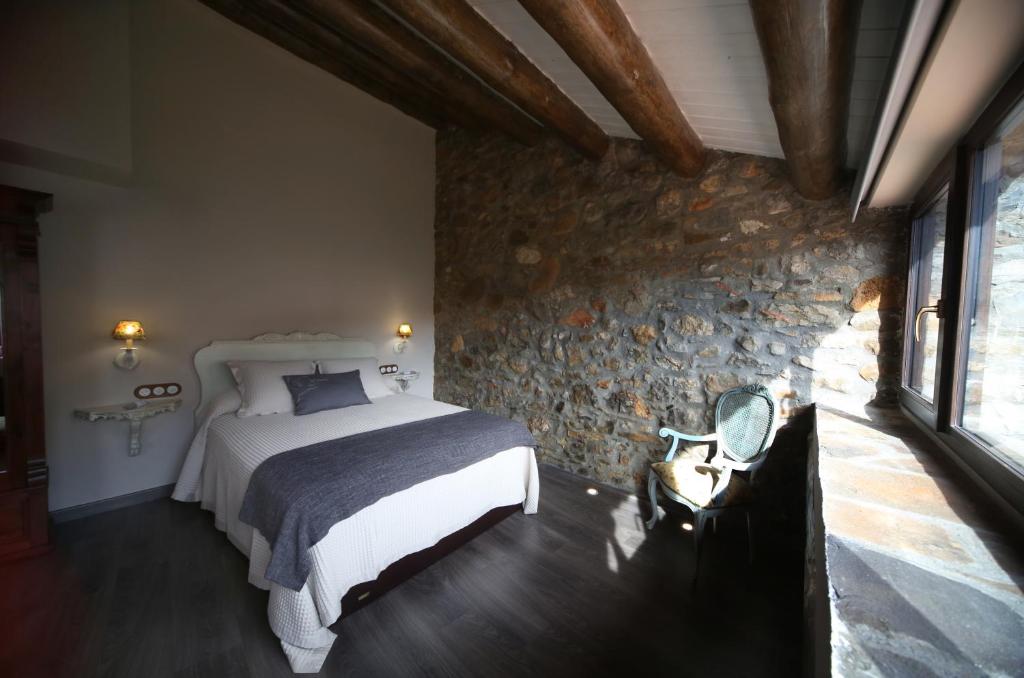 1 dormitorio con cama y pared de piedra en El Capricho de Nieves, en Laspuña