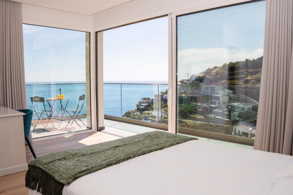a bedroom with a large window with a view of the ocean at Pérola de São João in Calheta