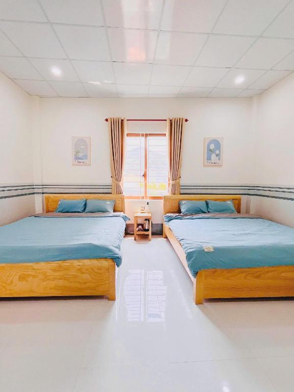 two twin beds in a room with a window at SUN Homestay Vĩnh Hy in Vĩnh Hy