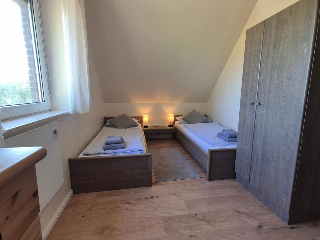 two beds in a small room with a window at Ferienwohnung zum Zander - Sonniger Weitblick übers Feld in Wester-Ohrstedt