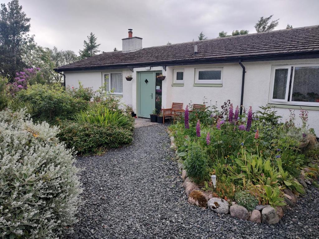 a white house with a garden in front of it at Cartmel in Aultbea