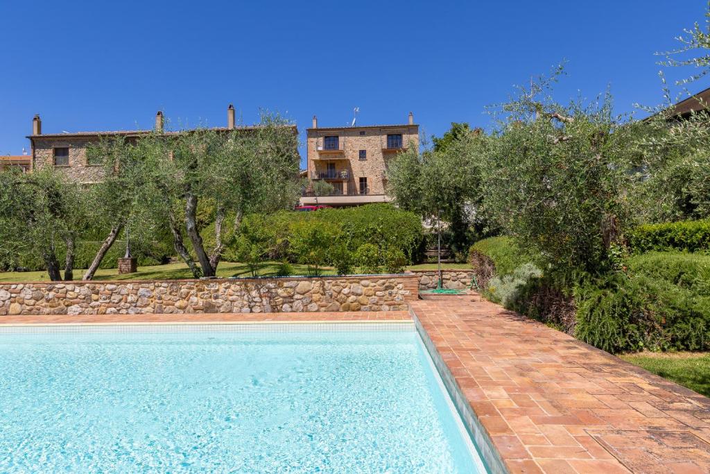 a swimming pool in a yard with a stone wall at Appartamento Rosmarino in Lajatico