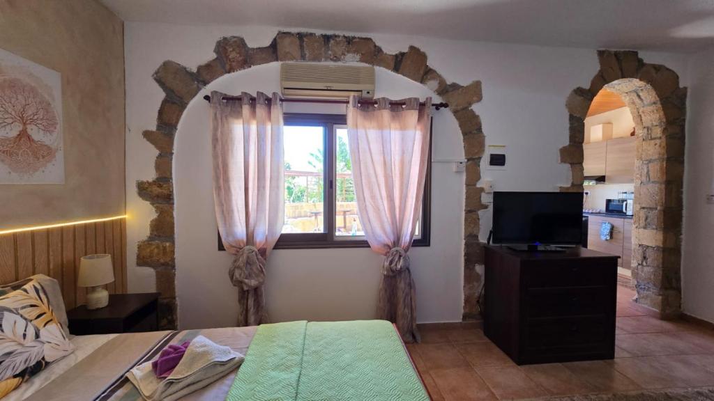 a bedroom with a bed and a window with pink curtains at Secluded Garden Studio in Tala