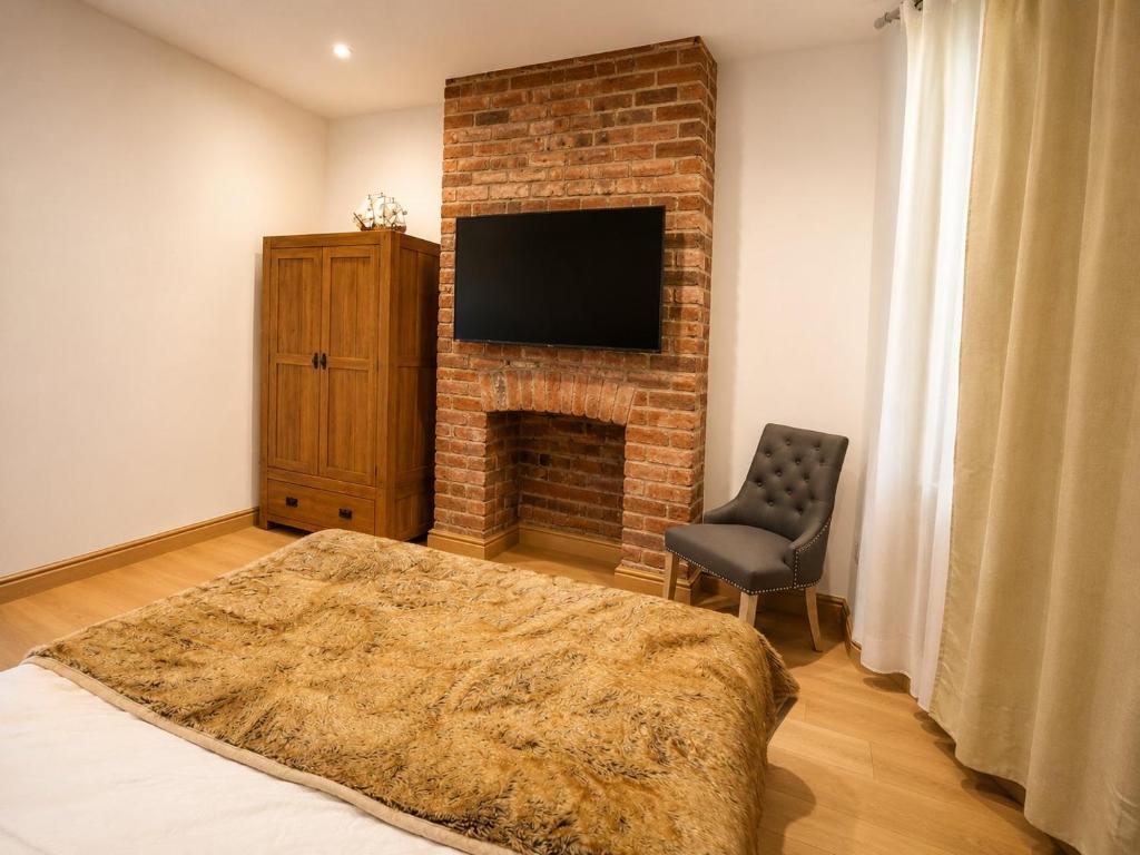 a living room with a brick fireplace and a chair at SidemerseyLivings - Step-Free 4BR Home, Ground Floor Bed & Bath, Private Gated Parking in Liverpool