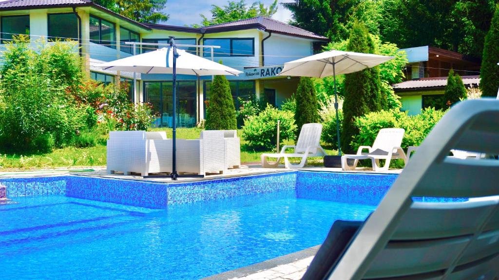 a swimming pool with chairs and umbrellas in front of a house at Rakovica Resort in Sarajevo