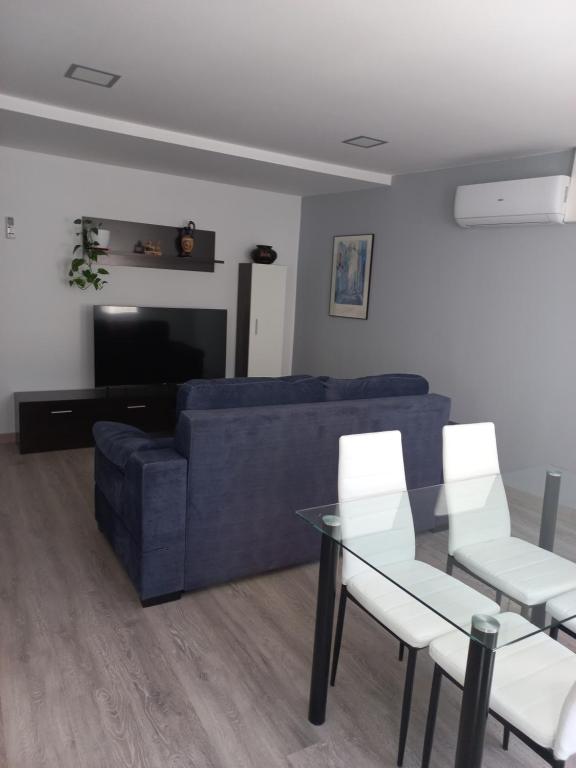 a living room with a blue couch and a glass table at Casa de la Soledad 2 in Lugo