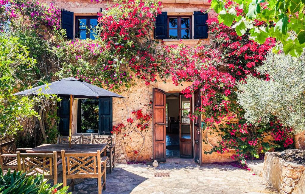 a house with a table and an umbrella and flowers at Ca'n Panxeta in Felanitx