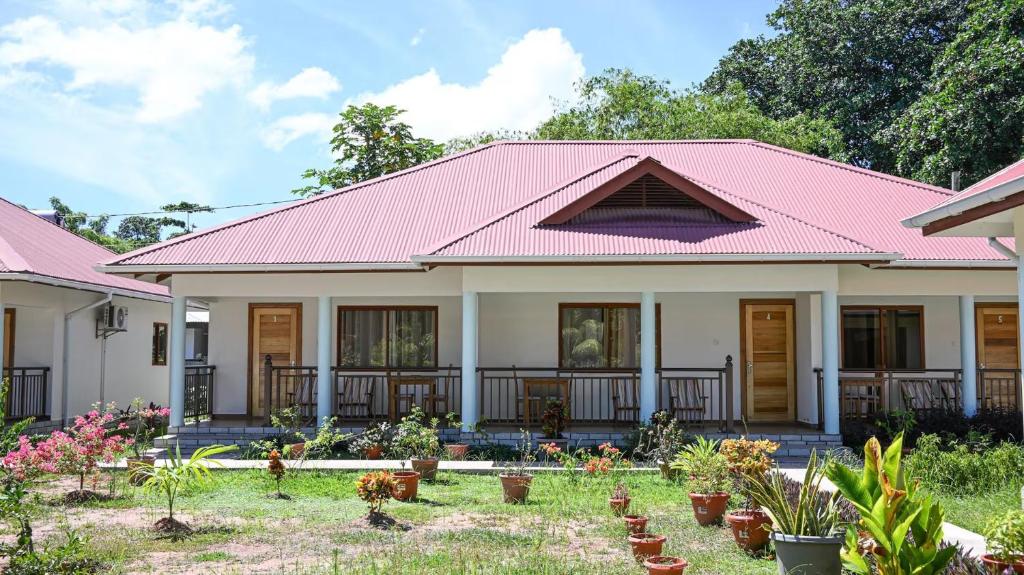 a house with a pink roof and some plants at La Maison Figaro Guest House - Spacious Island Stay in La Digue in La Réunion