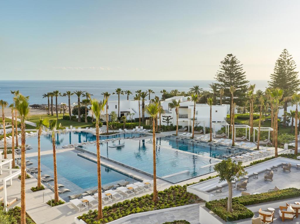 an aerial view of a resort pool with palm trees at Creta Palace, A Resort to Live in Rethymno
