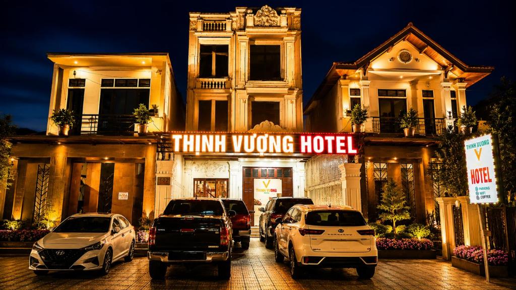 a building with cars parked in front of a think wrong hotel at Thịnh Vượng Hotel in Dong Hoi
