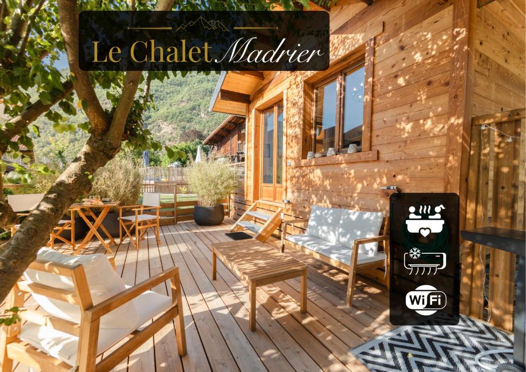 a porch of a log cabin with chairs and a grill at Le Chalet Madrier - Terrasse et Jacuzzi privé in Tours-en-Savoie