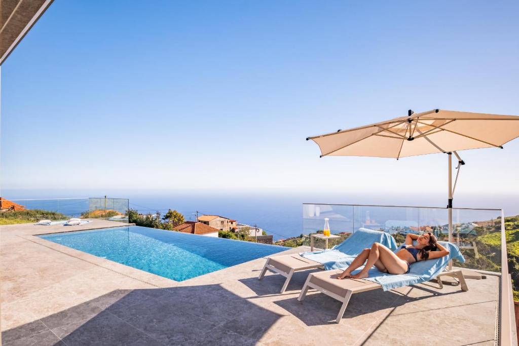 a couple sitting in a chair next to a swimming pool at Villa Platinum by Homie in Estreito da Calheta