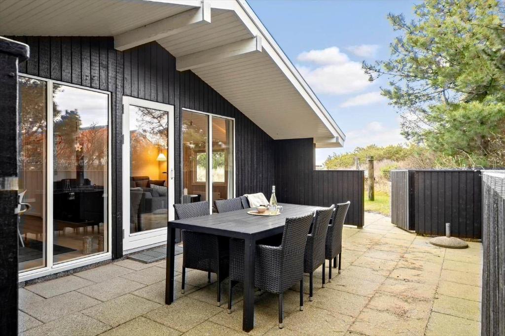 a dining table and chairs on a patio with a house at 239-Ringkobing-Vestklitvej-32 in Klegod