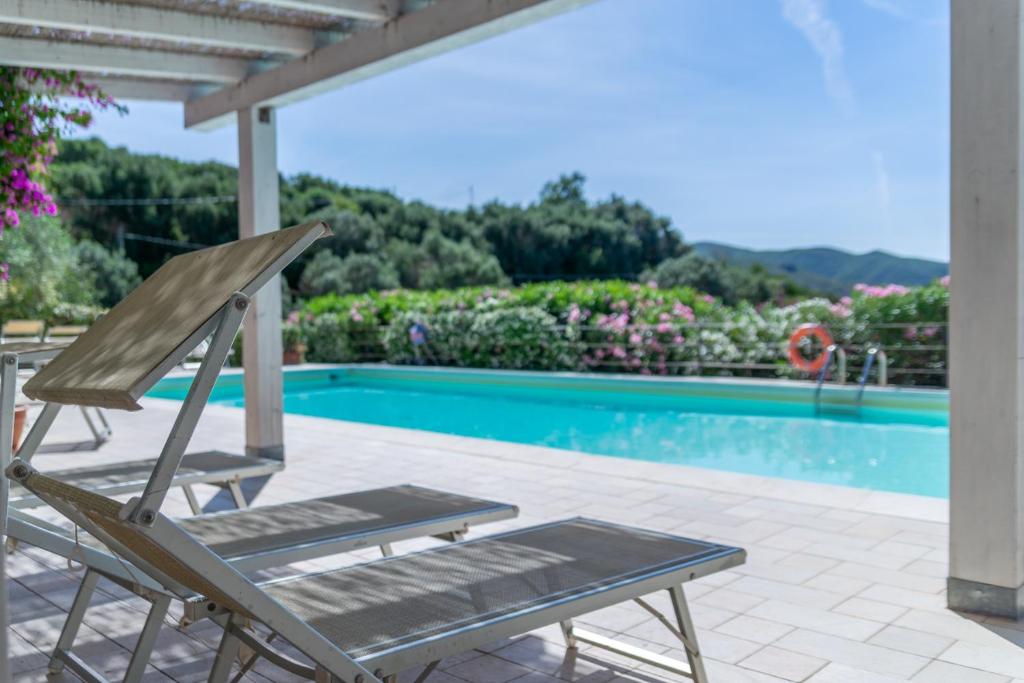 a wooden chair sitting next to a swimming pool at Appartamenti Le Solane - Goelba in Marmi