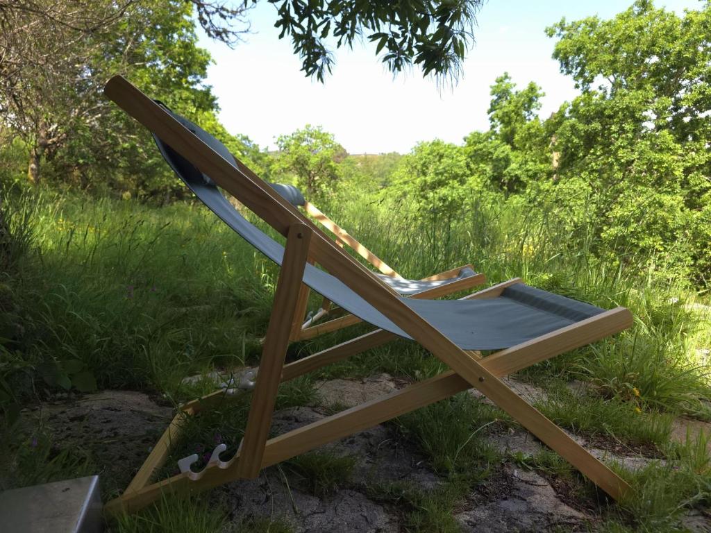 a chair sitting in the grass under a tree at Casa das Candeias in Melgaço