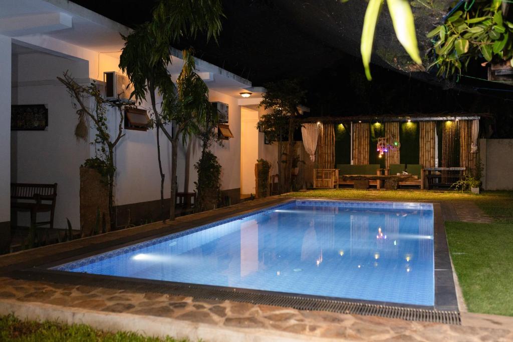 a swimming pool in a backyard at night at Rayonaz Resort in Dambulla