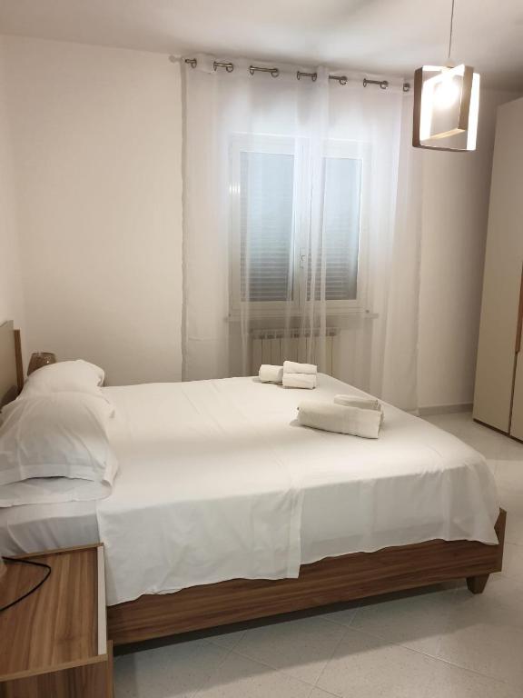 a bedroom with a bed with white sheets and a window at Sperlonga ad un passo Casa Vacanza in Sperlonga