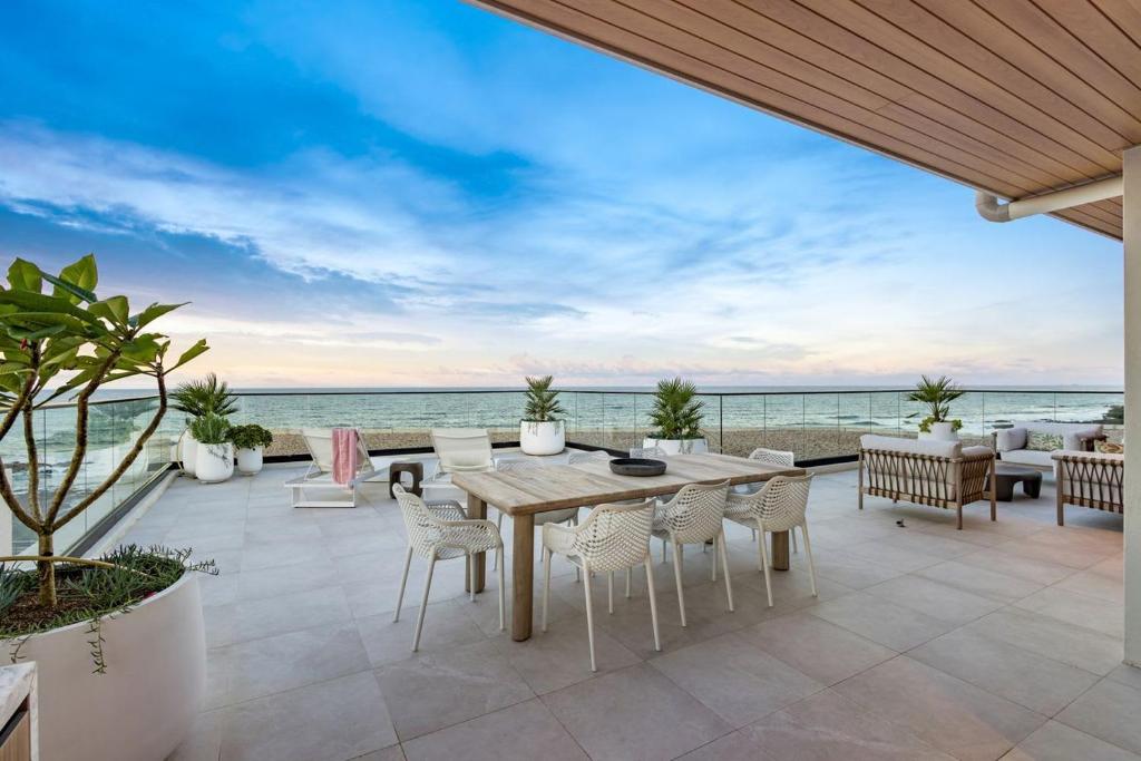 a patio with a table and chairs and the ocean at Penthouse at First Bay Coolum in Coolum Beach