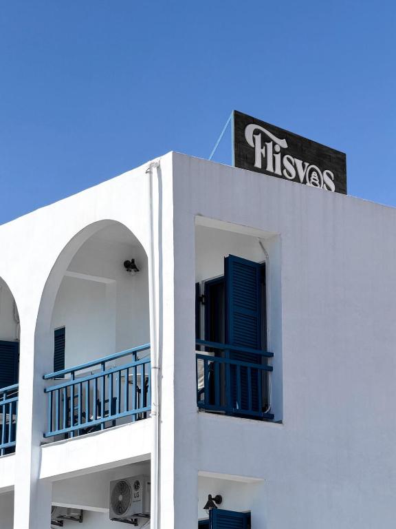 a white building with blue balconies and a sign on it at Hotel Flisvos in Megalochori