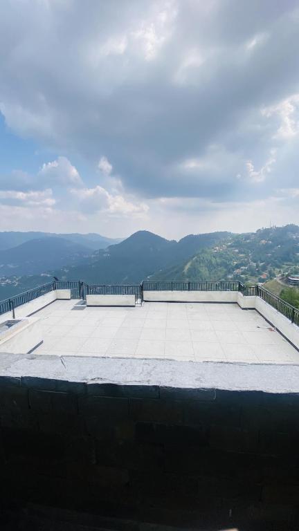 a person standing on top of a roof with mountains in the background at Luxury Apartment in Khaira Gali