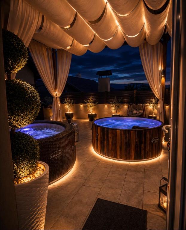 a room with two hot tubs on a patio at night at Holiday house "Mimoza" 2 massage pools in Otočac