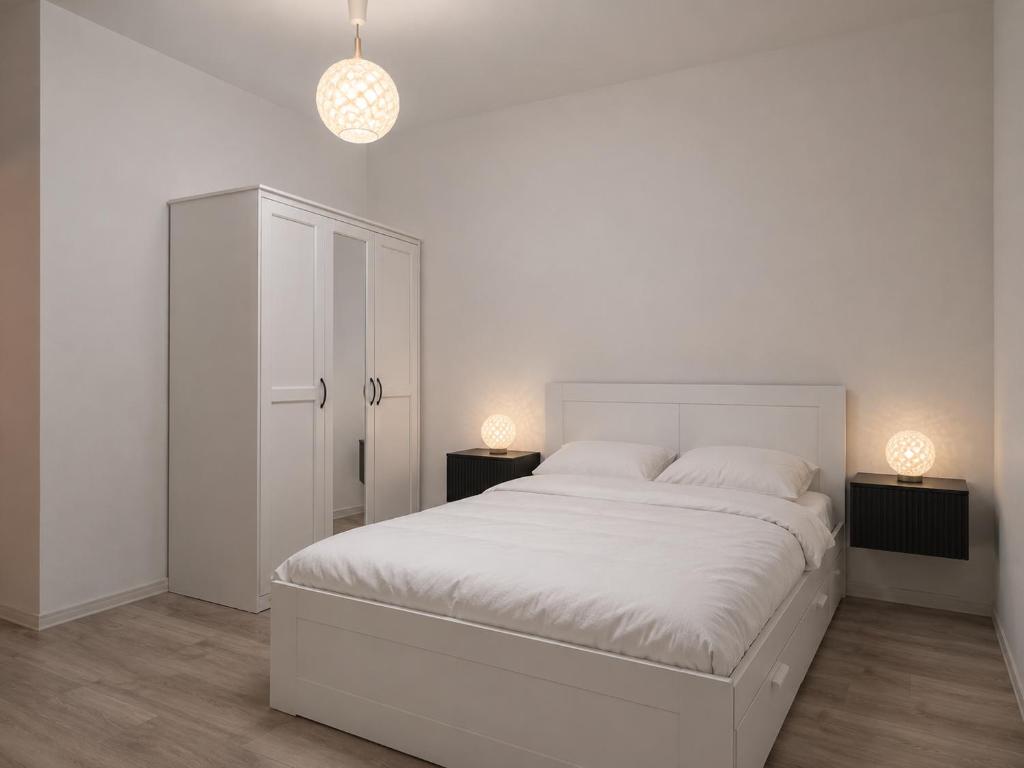 a white bedroom with a white bed and two lamps at Zielone drzwi in Żywiec